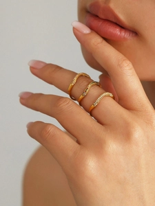 Set van drie goudkleurige golvende ringen met gekleurde zirkonia op een model