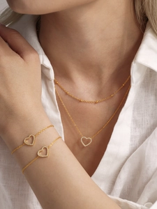 Détail d'un ensemble collier et bracelet cœur doré avec cristaux micro-pavés élégants