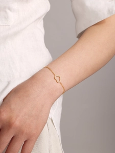 Détail macro du bracelet doré avec pendentif en forme de cœur serti de zircons brillants
