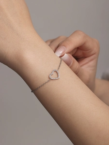 Détail d'un bracelet en argent avec pendentif cœur serti de zircons porté au poignet