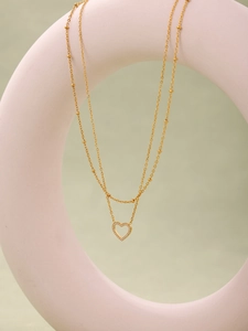 Vue détaillée d'un collier doré double épaisseur avec pendentif cœur serti de zircons