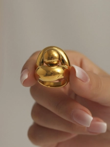 Vue rapprochée d'une bague dorée double couche avec sphère centrale au fini poli miroir