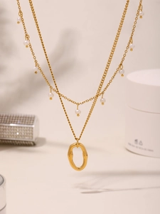 Detail of double-layer 18K gold plated necklace with small pearls and oval metal pendant
