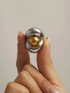 Détail d'une bague bicolore en acier inoxydable avec cadre argenté et bille dorée