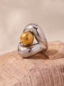 Gros plan sur une bague cœur en argent poli avec bille dorée sur pierre naturelle