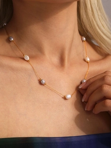 Detail of elegant gold chain necklace featuring white and lavender freshwater pearls