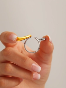 Macro shot of bicolour fluid design open ring in gold and silver plating