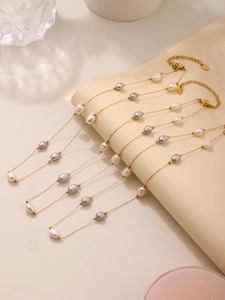 Macro view of gold stainless steel necklace with white and purple baroque pearls