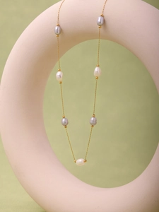 Detail of baroque pearl necklace with white and purple pearls on a gold chain strand