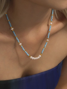 Close-up of model wearing blue turquoise and freshwater pearl necklace with gold beads