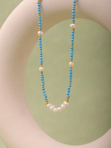 Detail of blue turquoise beads and freshwater pearls on a gold stainless steel necklace