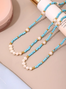 Detail of beaded necklace with blue turquoise and white pearls on cream bottle