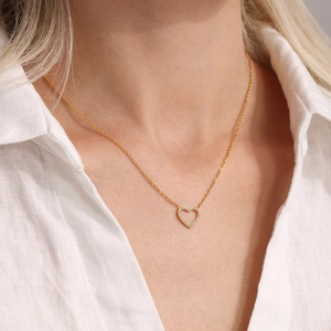 Collier élégant avec pendentif cœur doré et cristaux de zircon sur chemise blanche