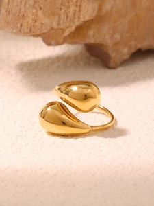 Detail of adjustable bypass ring with gold-plated water drop design on natural rock