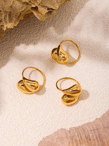 Close-up of three 18K gold plated teardrop rings on sand with shells and stones
