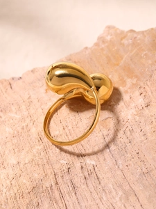 Macro shot of minimalist gold teardrop ring on natural stone with mirror finish