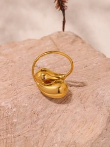Detailed macro view of gold-plated fluid teardrop ring on natural textured stone