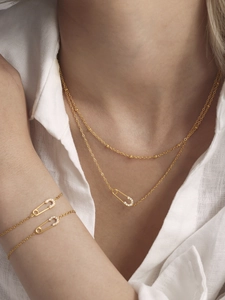 Detail of gold safety pin jewelry set with 5A zircon inlay worn by a model