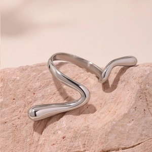 Polished silver irregular wave ring in a minimalist open design on natural stone