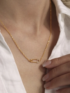Close-up of a gold safety pin necklace with 5A zircon inlay on a model neck