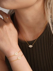 Close-up of gold evil eye necklace and layered bracelet set with sparkling cubic zirconia