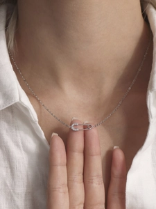 Detailed view of silver safety pin pendant necklace with zircon inlay on a model