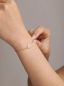 Detail of gold evil eye bracelet with white zircon pave setting on a delicate chain
