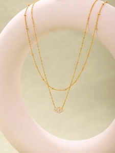 Close-up of golden double-layered satellite chain necklace with evil eye zircon pendant