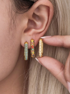 Detail shot of three 20mm geometric gold earrings with colorful zircon and stones