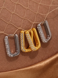 Close-up of gold and silver U-shaped hoop earrings with pave-set shimmering crystals