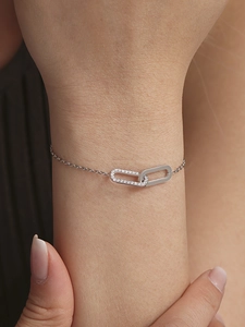 Close-up of a silver-tone chain bracelet with interlocking cubic zirconia square pendants