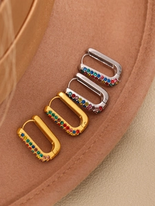 Detail of gold and silver U-shaped hoop earrings with colorful rainbow gemstones