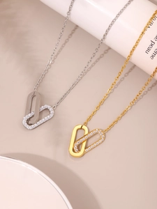 Detail view of interlocking silver and gold pendant necklaces with white cubic zirconia pavé