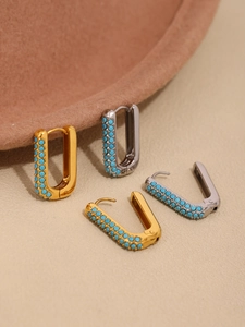 Detail of gold and silver U-shaped hoop earrings with inlaid turquoise blue beads