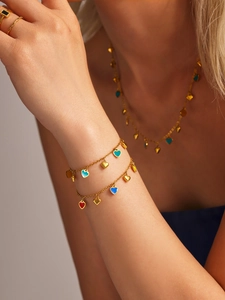 Detail of model wearing a gold jewelry set with colorful enamel heart pendants