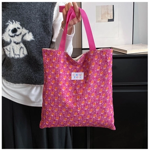 Detail of pink floral tote bag showing textured fabric and branded woven logo tag