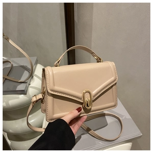 Detail van beige crossbodytas met gouden ovale ringsluiting en gladde lederen afwerking