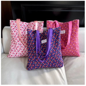 Floral quilted tote bag in pink and blue colors shown on a white leather sofa