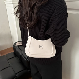 Minimalist cream white crescent bag with metallic bow buckle shown on model shoulder