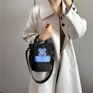 Mini canvas crossbodytas in zwart en blauw met pixelontwerp, getoond op een model