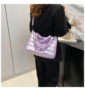 Macro detail of purple quilted nylon puffer bag with adjustable black shoulder strap