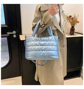 Close-up of light blue quilted puffer bag with metallic finish and cylindrical handles