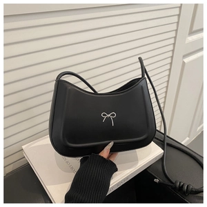Dettaglio borsa a spalla nera con fibbia a fiocco argento e design curvo minimalista