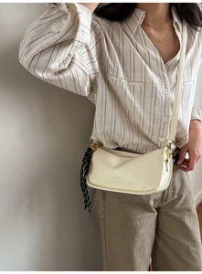 Close-up of cream PU leather crossbody bag featuring fashion embossing and a striped scarf charm