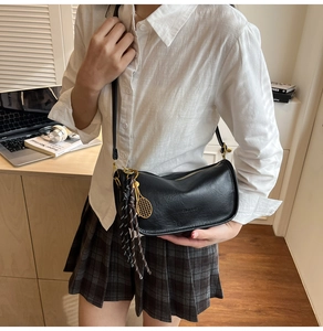 Détail du sac croissant en cuir noir avec pendentif raquette de tennis doré et gland