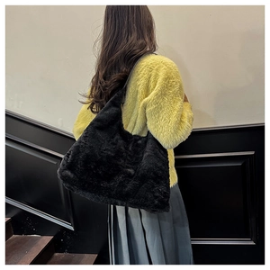 Detail of soft black plush tote bag worn over shoulder with fluffy faux fur texture