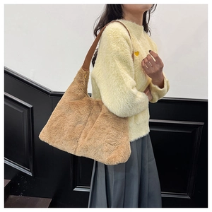 Detail of khaki plush tote bag with brown leather strap and gold zipper on a winter outfit
