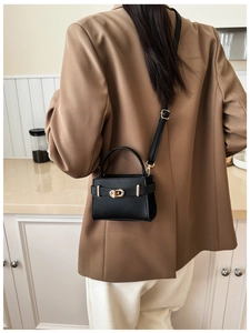 Close-up of black textured leather square bag with gold buckle and stylish top handle
