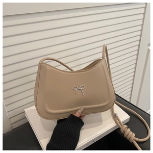 Dettaglio borsa a tracolla beige in pelle con fiocco in argento e tracolla a nodi