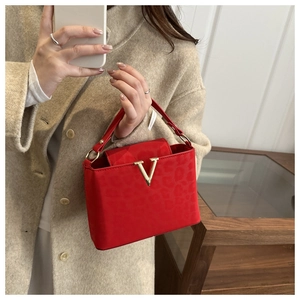 Close-up of red faux suede handbag with leopard pattern and gold V-shaped buckle